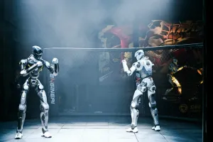 Two URKL T800 robots facing off in fighting stances inside the fenced arena