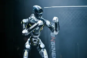 URKL T800 robot in a boxing stance with both fists raised in the cage