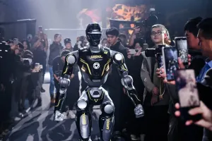 URKL T800 robot entering the arena as photographers crowd around with cameras and phones