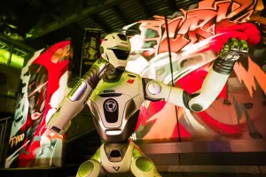 URKL T800 robot posing with an arm raised in front of arena graffiti art