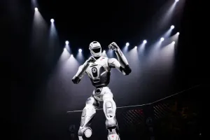 URKL T800 robot raising both fists under spotlights in the cage