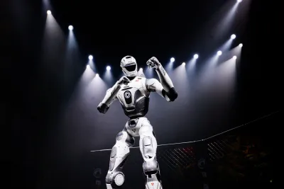 URKL T800 robot raising a fist in the fight cage under stage lights