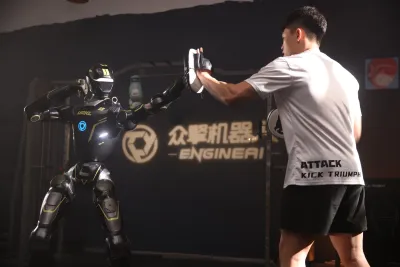 URKL T800 robot training with focus mitts alongside a human coach in the EngineAI gym